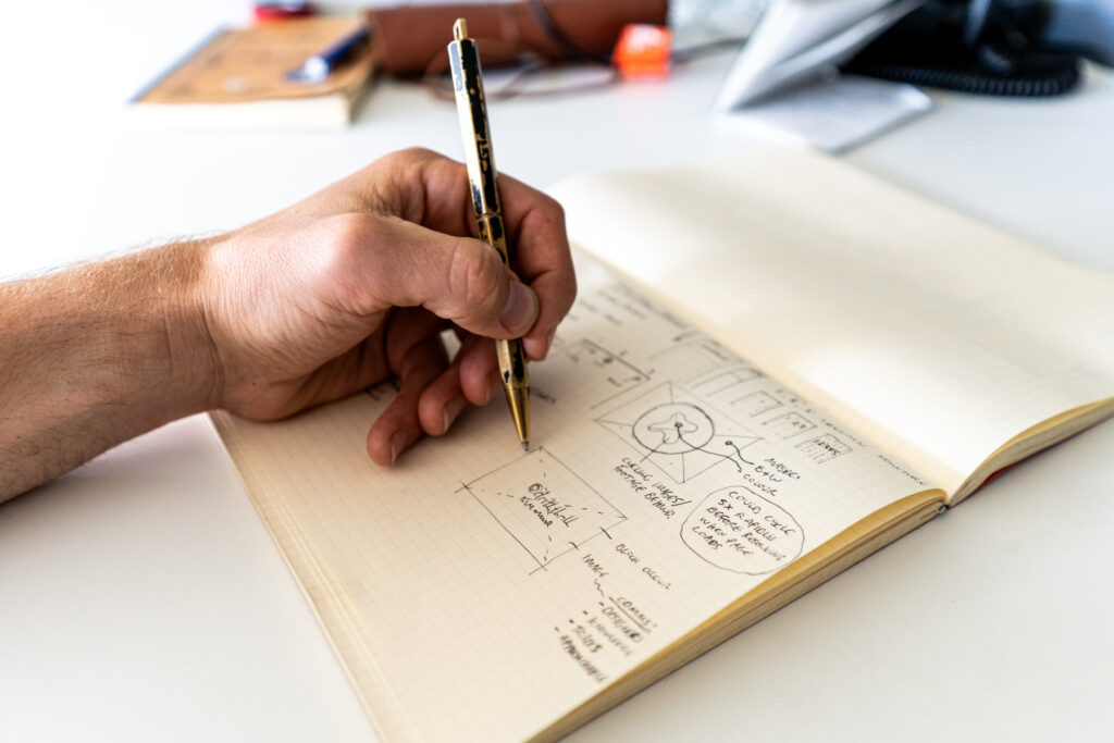 close up of a man writing ideas for a website design on a notebook