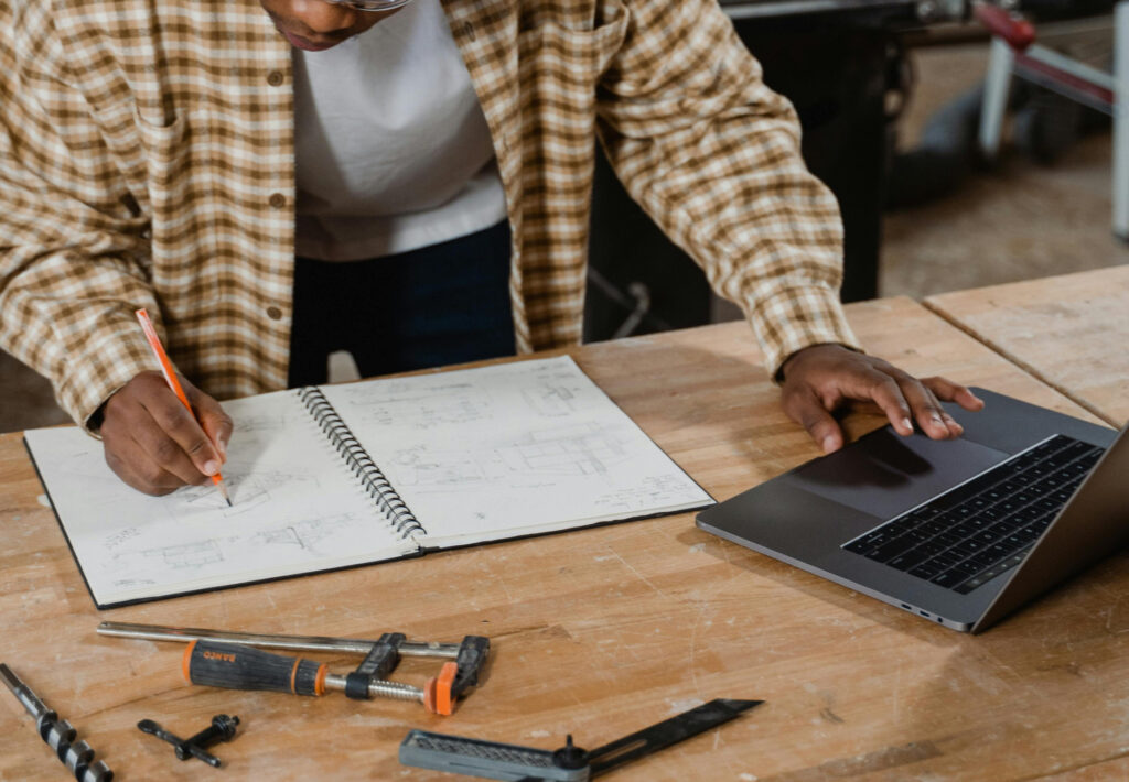 a carpenter drawing ideas on a notebook in his workshop